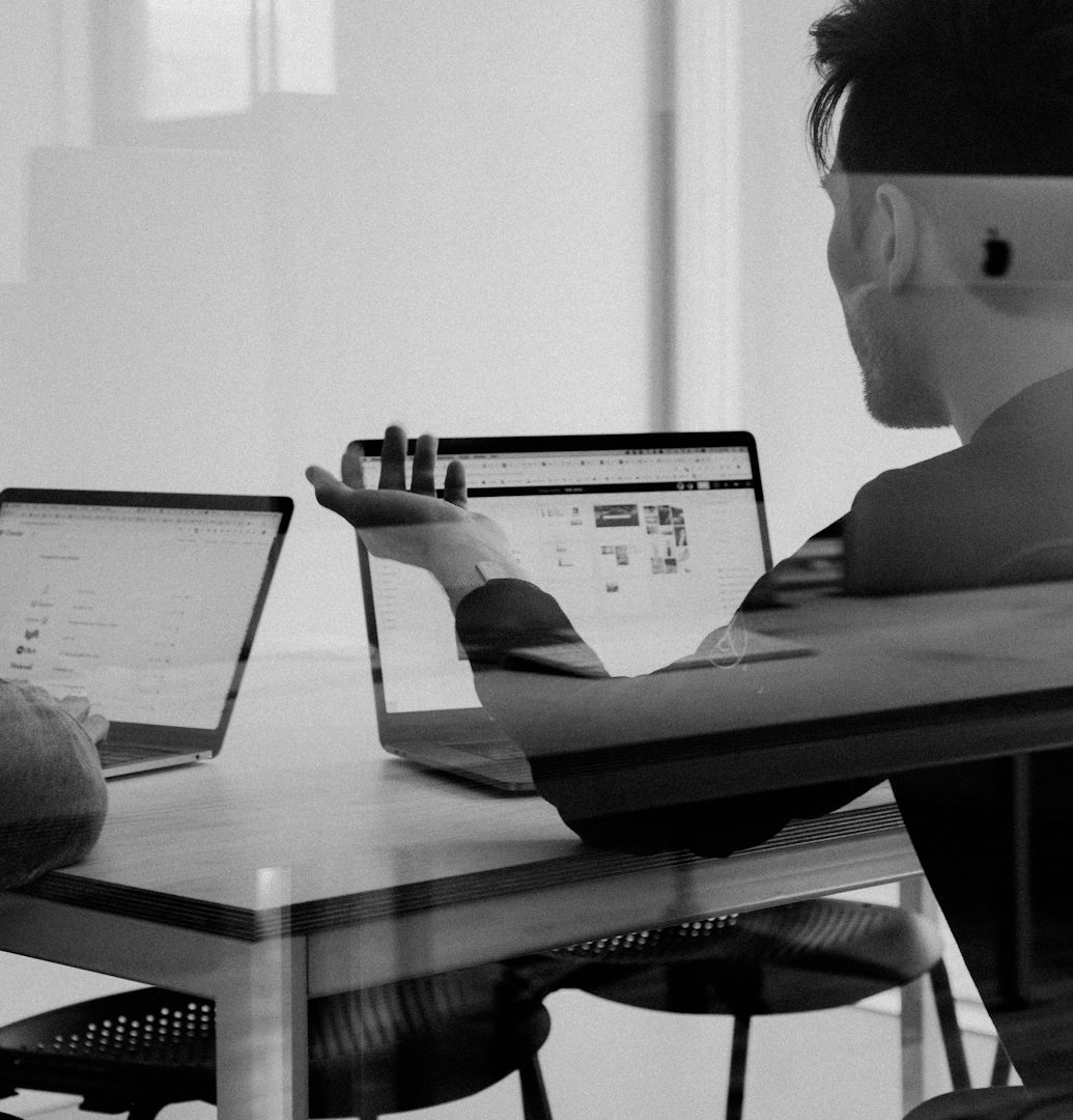 konzept M Akademie Zwei Personen arbeiten an Laptops in einem modernen Büro.
