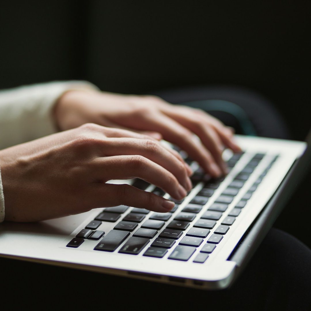 Wachstum Hände tippen auf einer Laptop-Tastatur, dunkler Hintergrund.